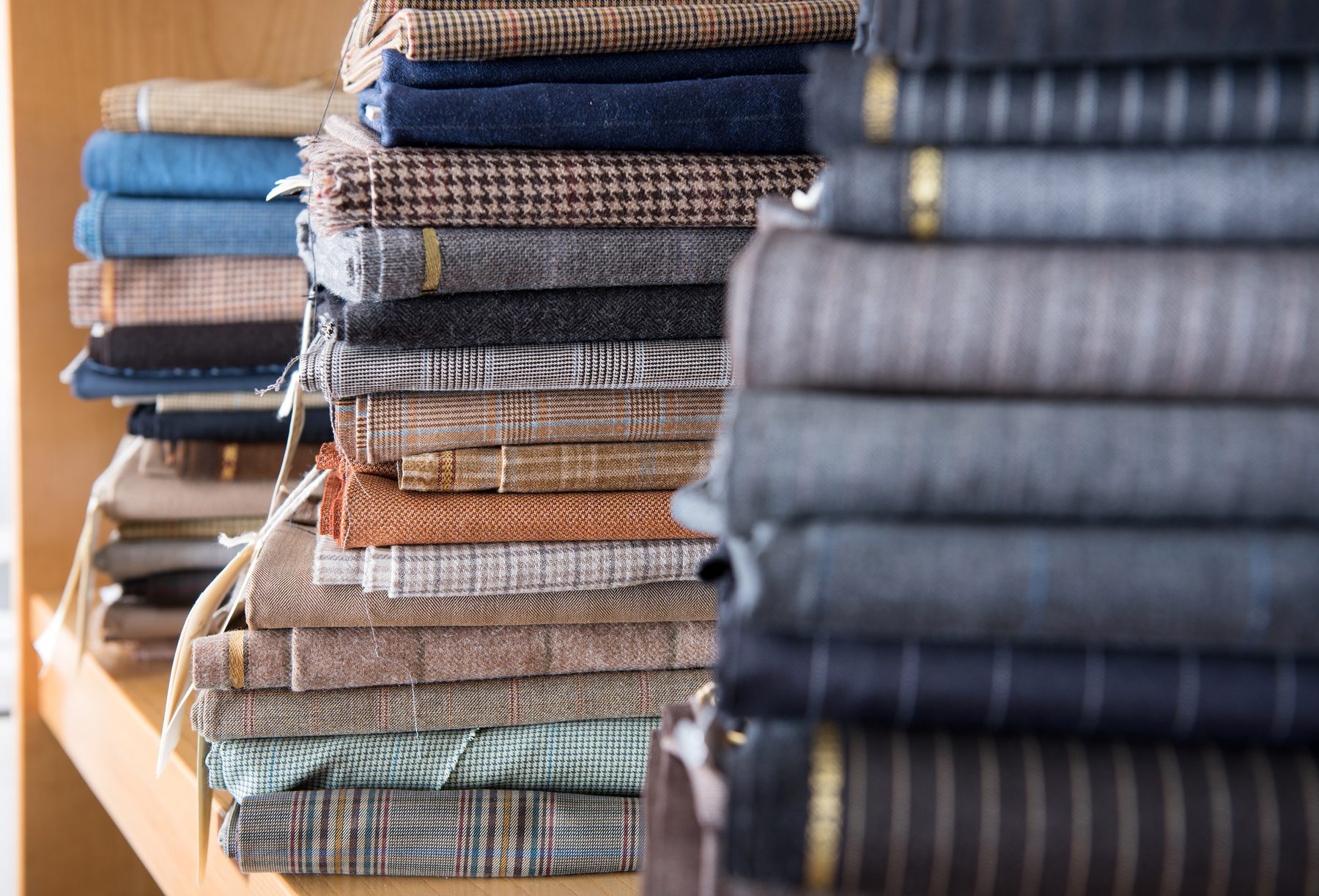 Piles de tissus de tailleur pliés : pied-de-poule, carreaux, chevrons et unis